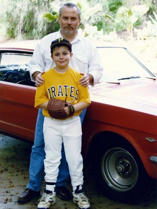 Ian in baseball unifrom with Mark in front of Mark's Mustang